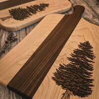 Handmade maple and walnut chopping boards with wood burned pine trees