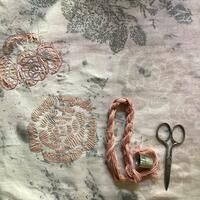 Eco printed rose leaves, hand embroidered roses, thread and scissors on fabric. 