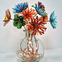 Kiln-formed glass flowers on unique copper stems designed by myself, displayed in a recycled glass vase