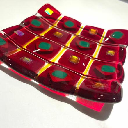 Red glass shallow bowl with textured edges and coloured inserts