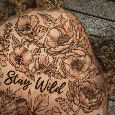 Wood burned botanical art surrounding wording "Stay Wild' 