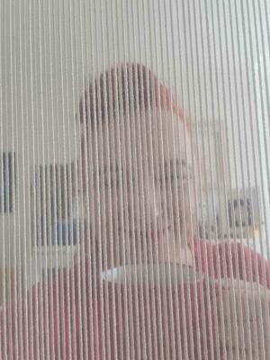 Picture of Karen Hiser viewed through the warp threads holding a cup