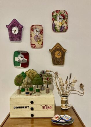 Display of fabric clocks on the wall and cotton reel trees